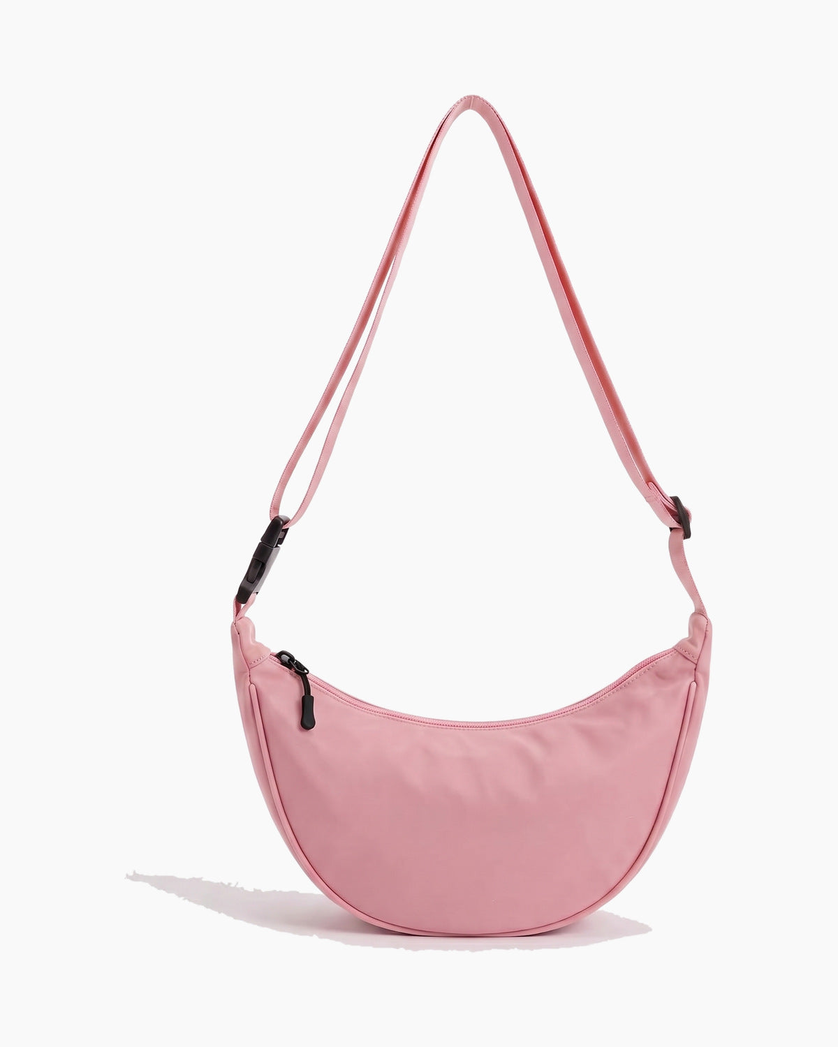Pink sling bag with a crescent body and a single top zip, on a plain background