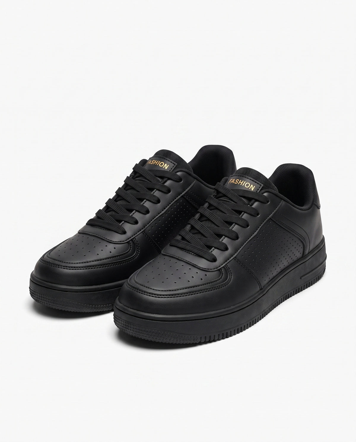 Black low top sneaker with perforated panels, gold tongue mark and a thick moulded sole, studio product shot