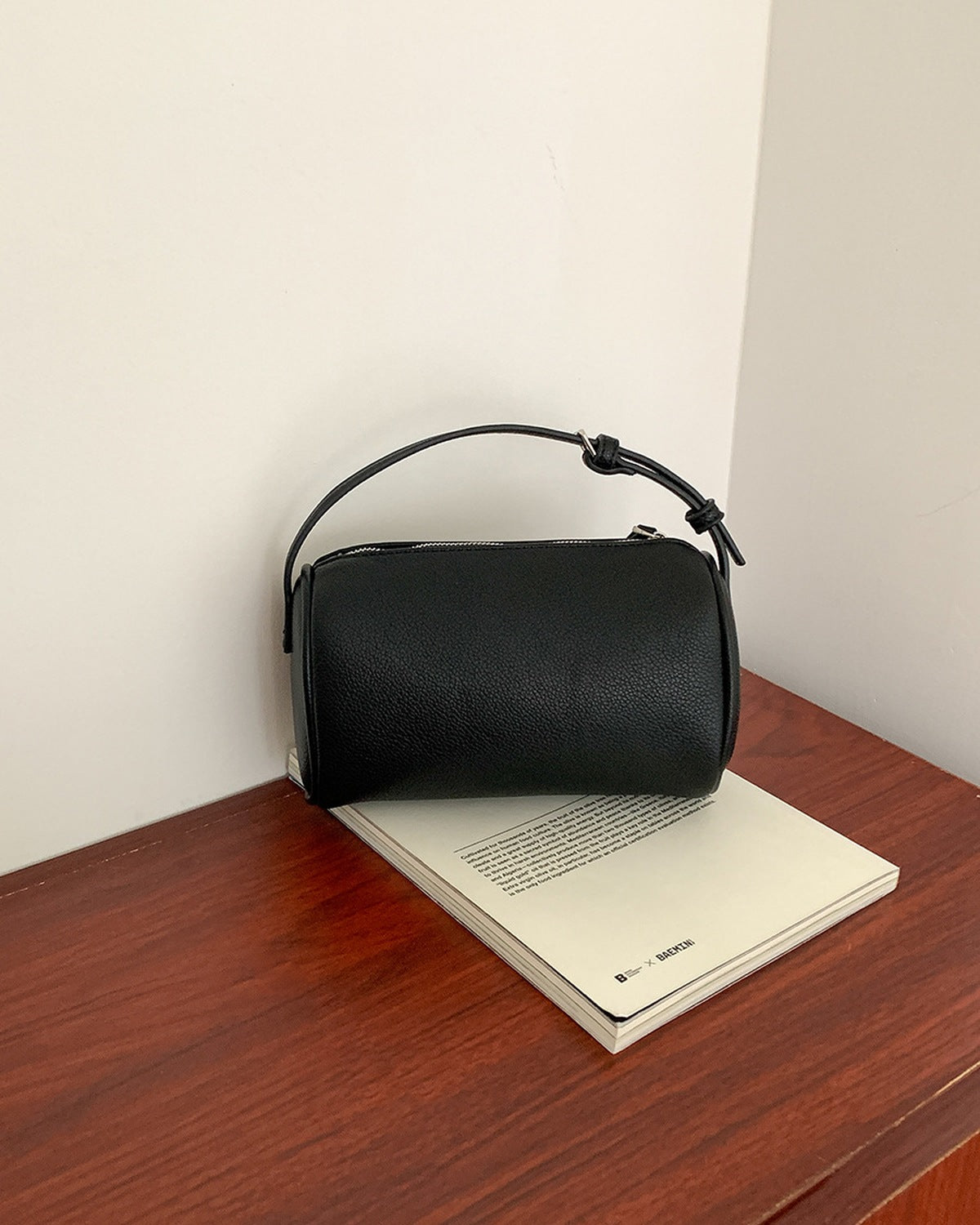 Black zip crossbody bag resting on a desk