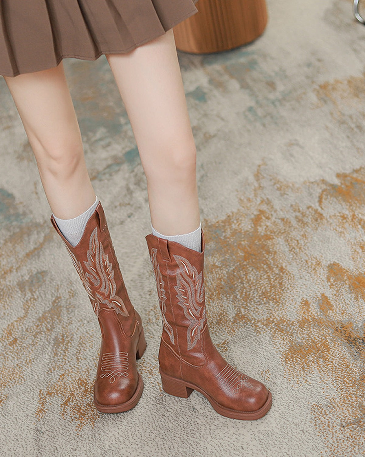Brown cowboy boots worn with a pleated skirt