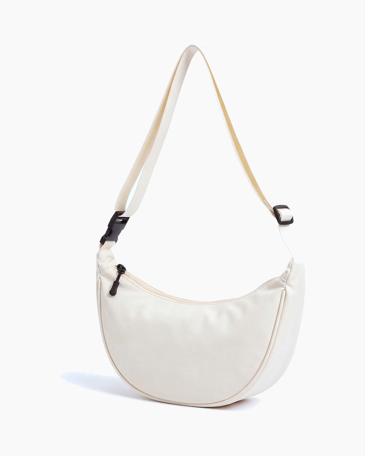 Off-white sling bag turned to show its depth and side, on a plain background
