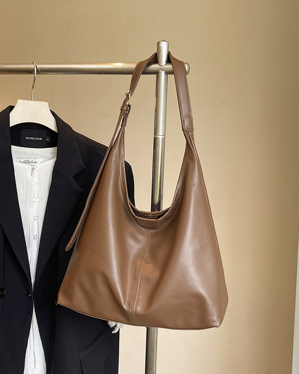 Brown slouchy shoulder bag hanging from a rail
