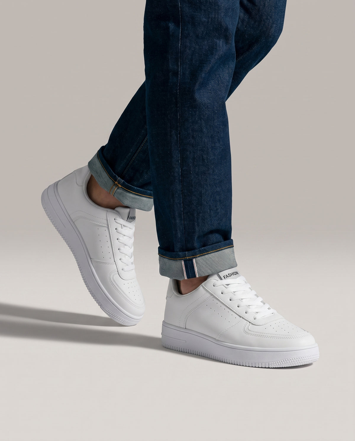 Model mid-stride wearing white low top sneakers, low-angle studio shot