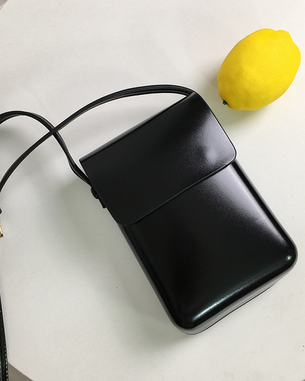 Black mini crossbody bag styled on a table