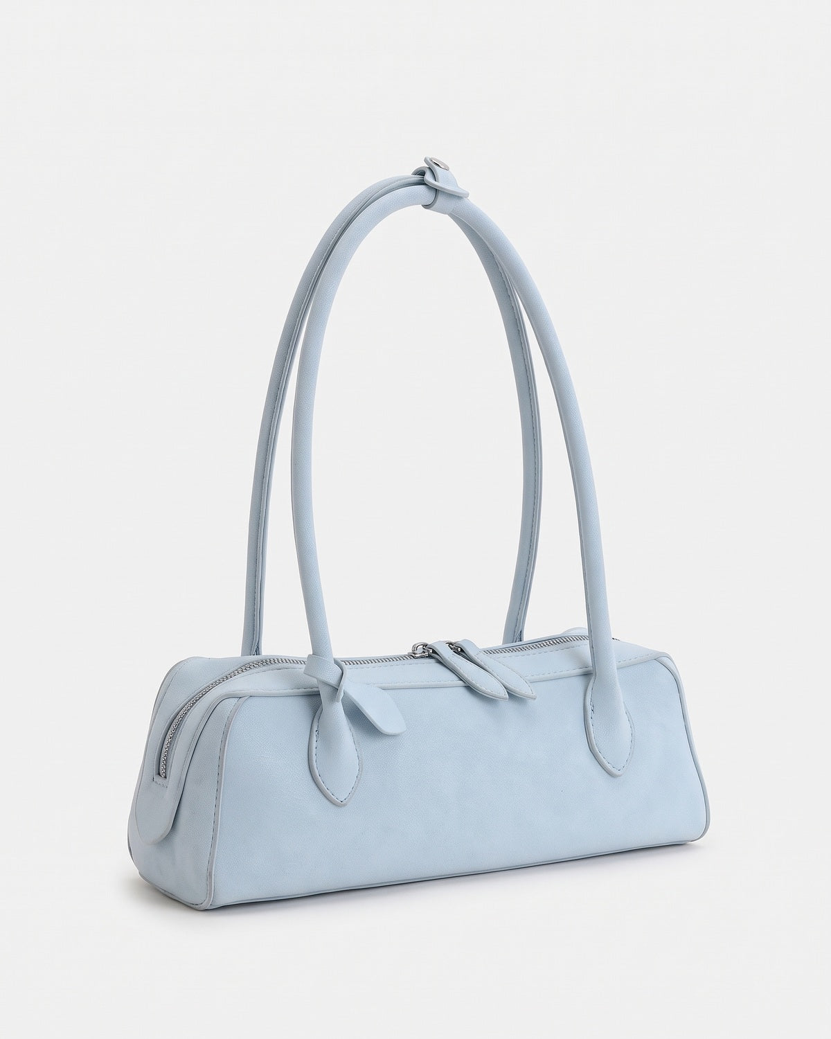 Light blue suede baguette bag with knotted end tabs and twin short straps, three-quarter view on a plain background