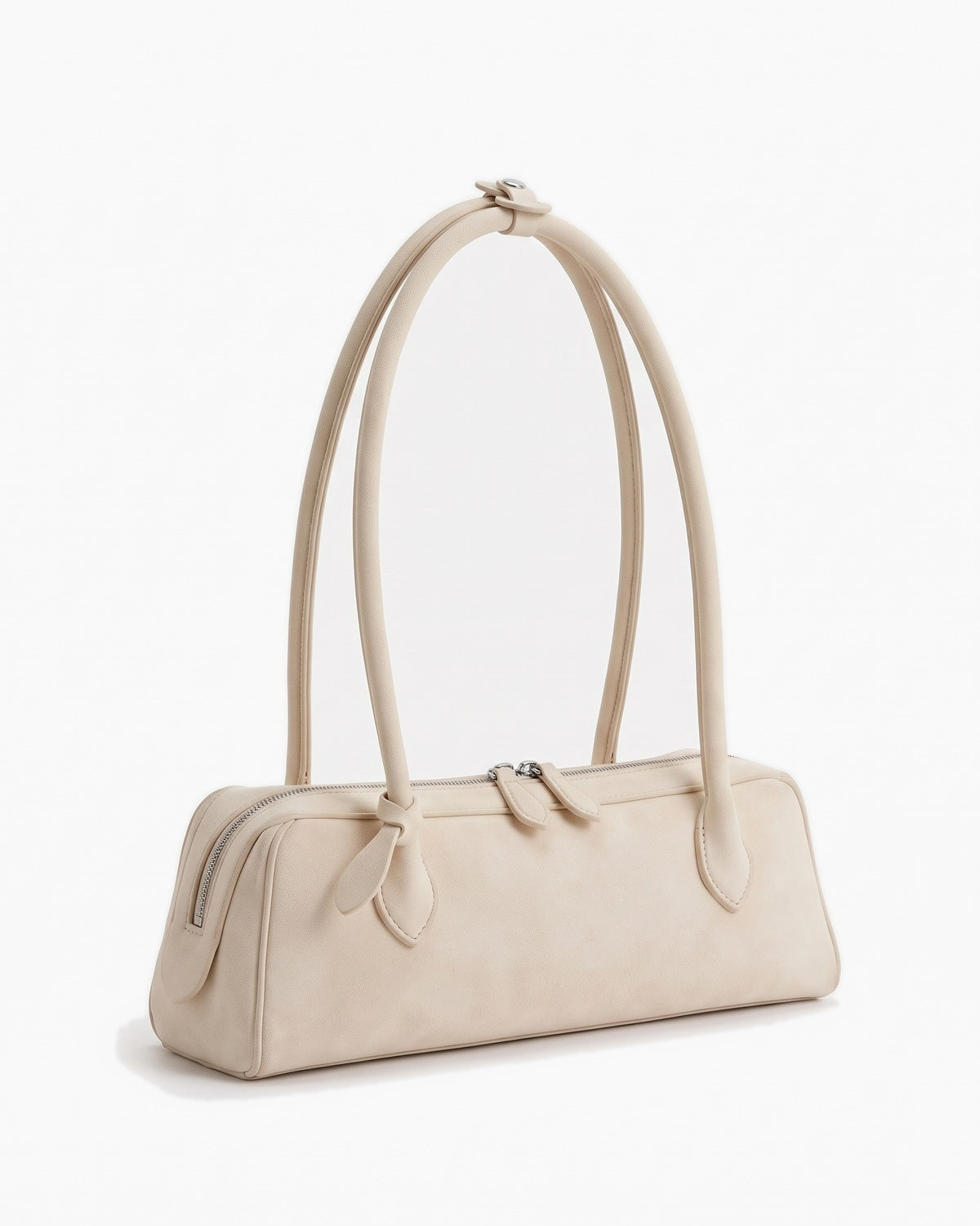 Soft ivory suede baguette bag with knotted end tabs, three-quarter view on a plain background