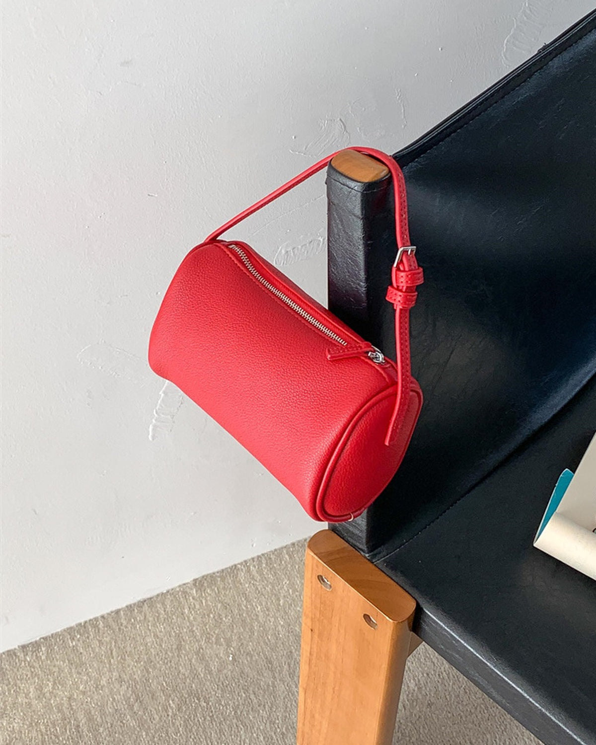 Red zip crossbody bag hanging over the back of a chair